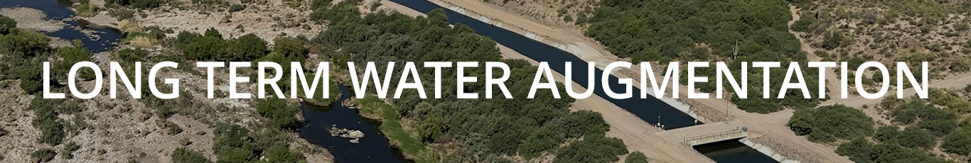 Sonoran desert view. the image includes green shrubs, a riverbed with water, and the central arizona canal. the image has a text overlay that reads 