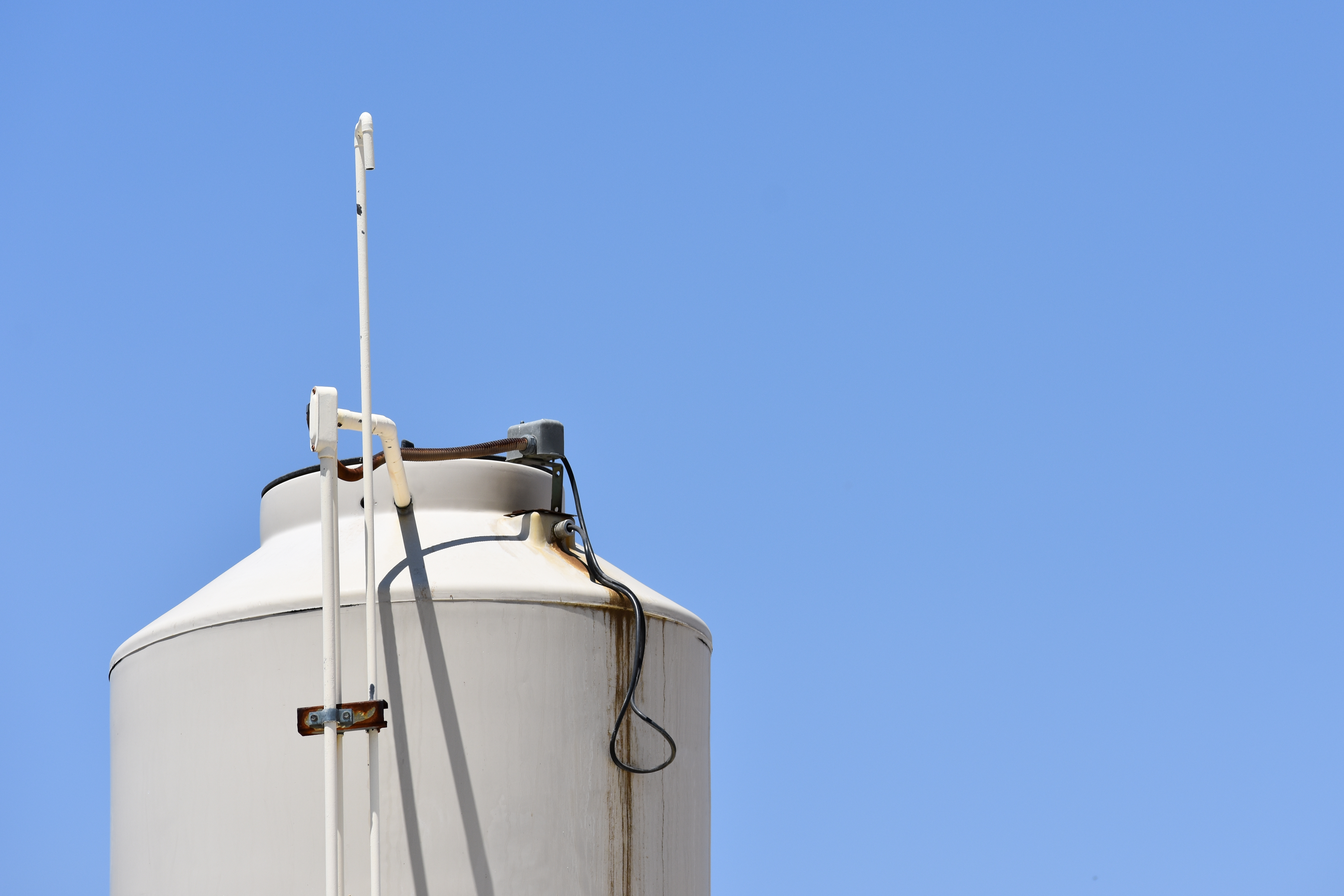 Blue sky featuring the top of a water storage tank
